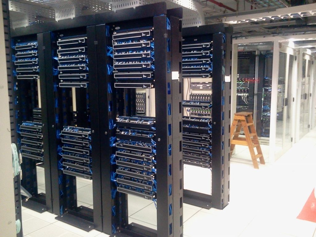 Rows of server racks with blue cabling in a bright data room
