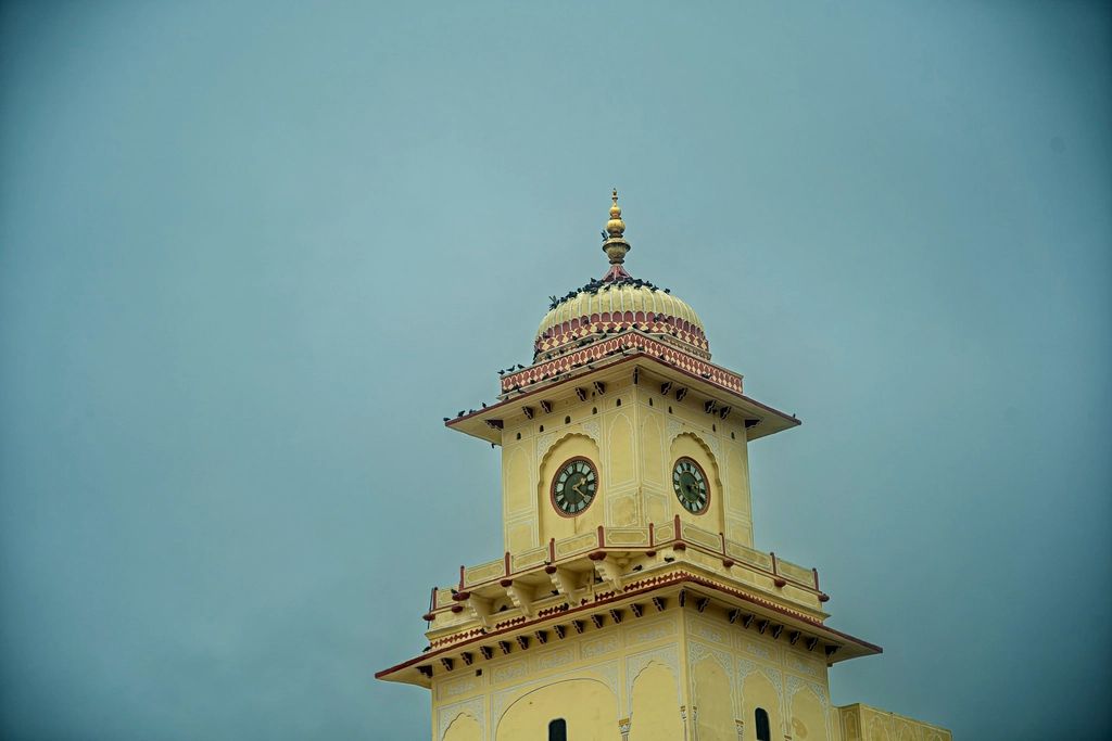 A clock tower with two clock faces against a grey sky in Jaipur, India