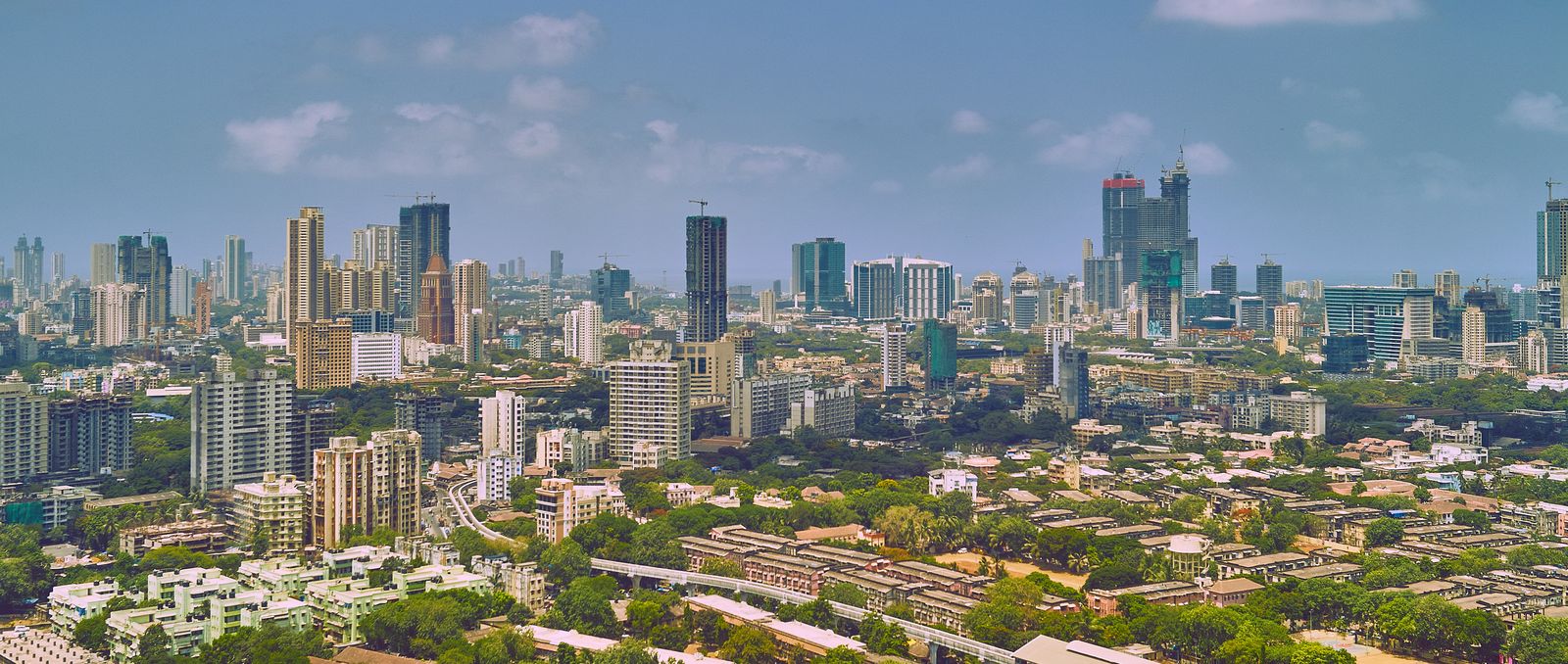 A wide view of the Mumbai skyline with high-rise towers and low-rise neighbourhoods