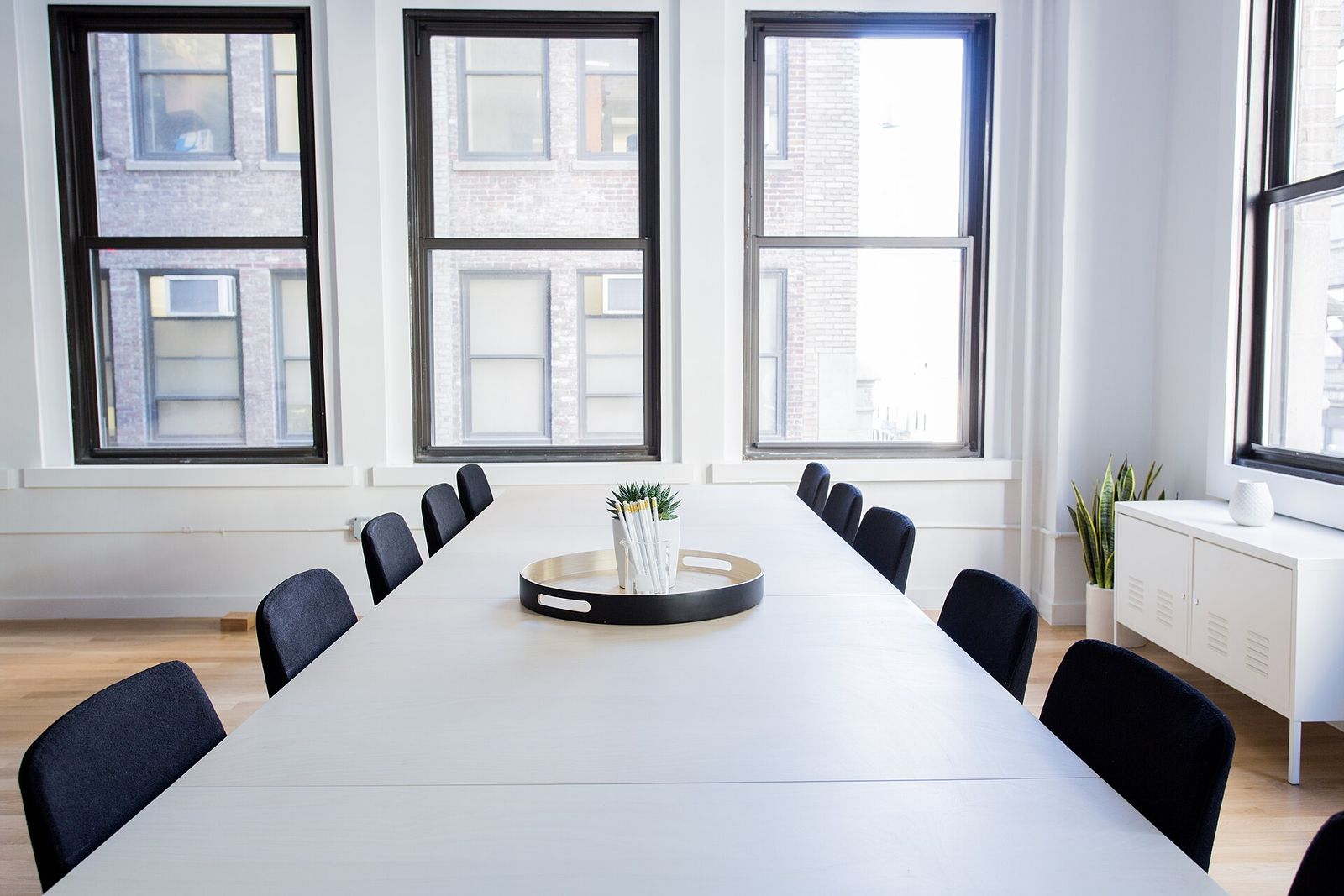 A bright, empty meeting room with a long white table and tall windows