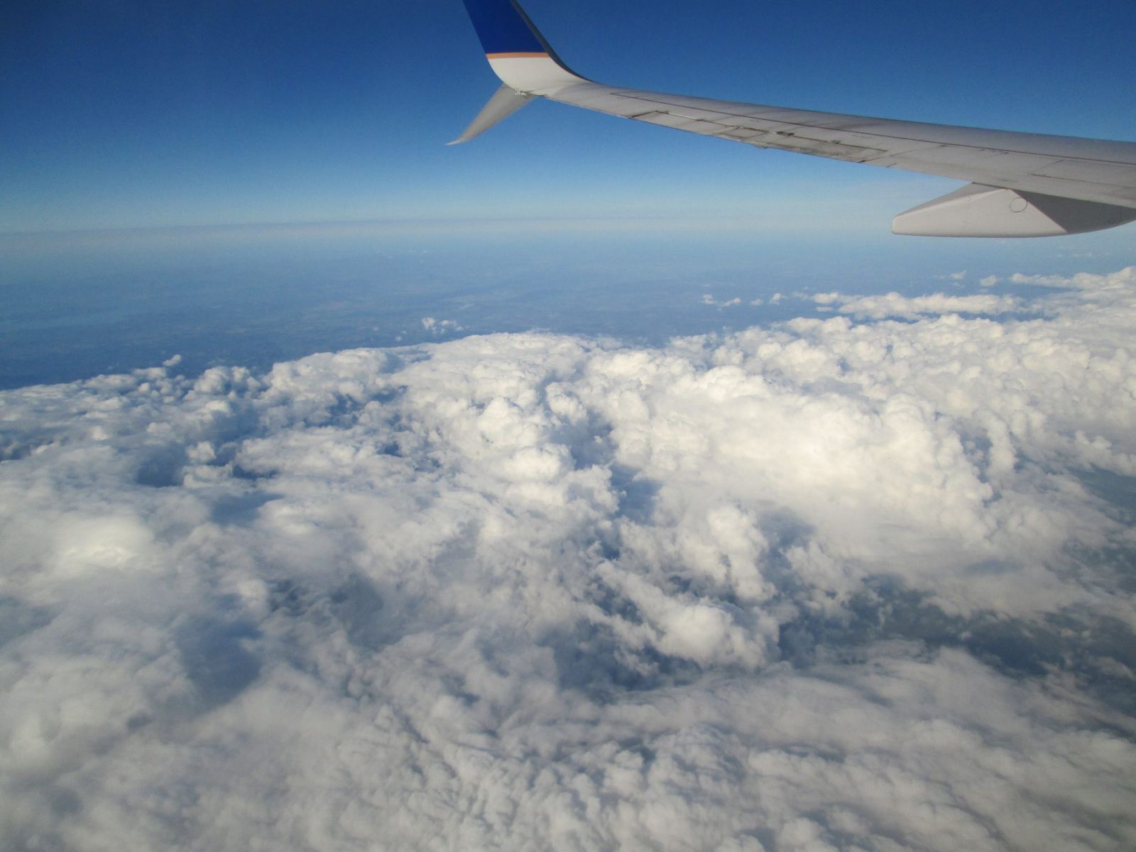 An aircraft wing above a layer of white clouds