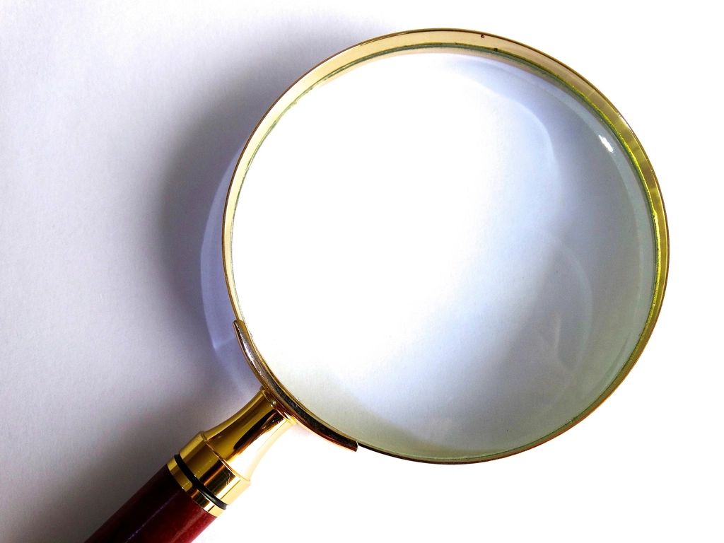 A large magnifying glass with a gold rim on a white surface