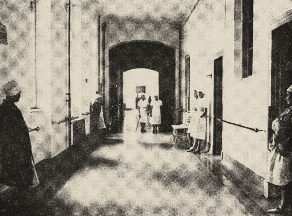 A 1931 photograph of a long hospital corridor with arched doorways
