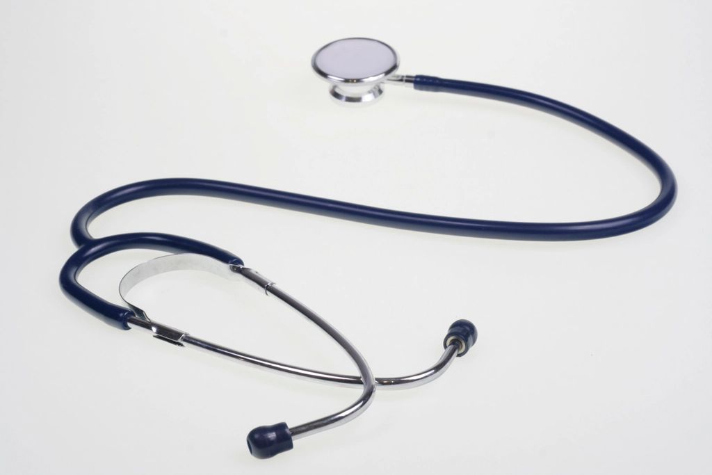 A navy blue stethoscope on a plain white surface
