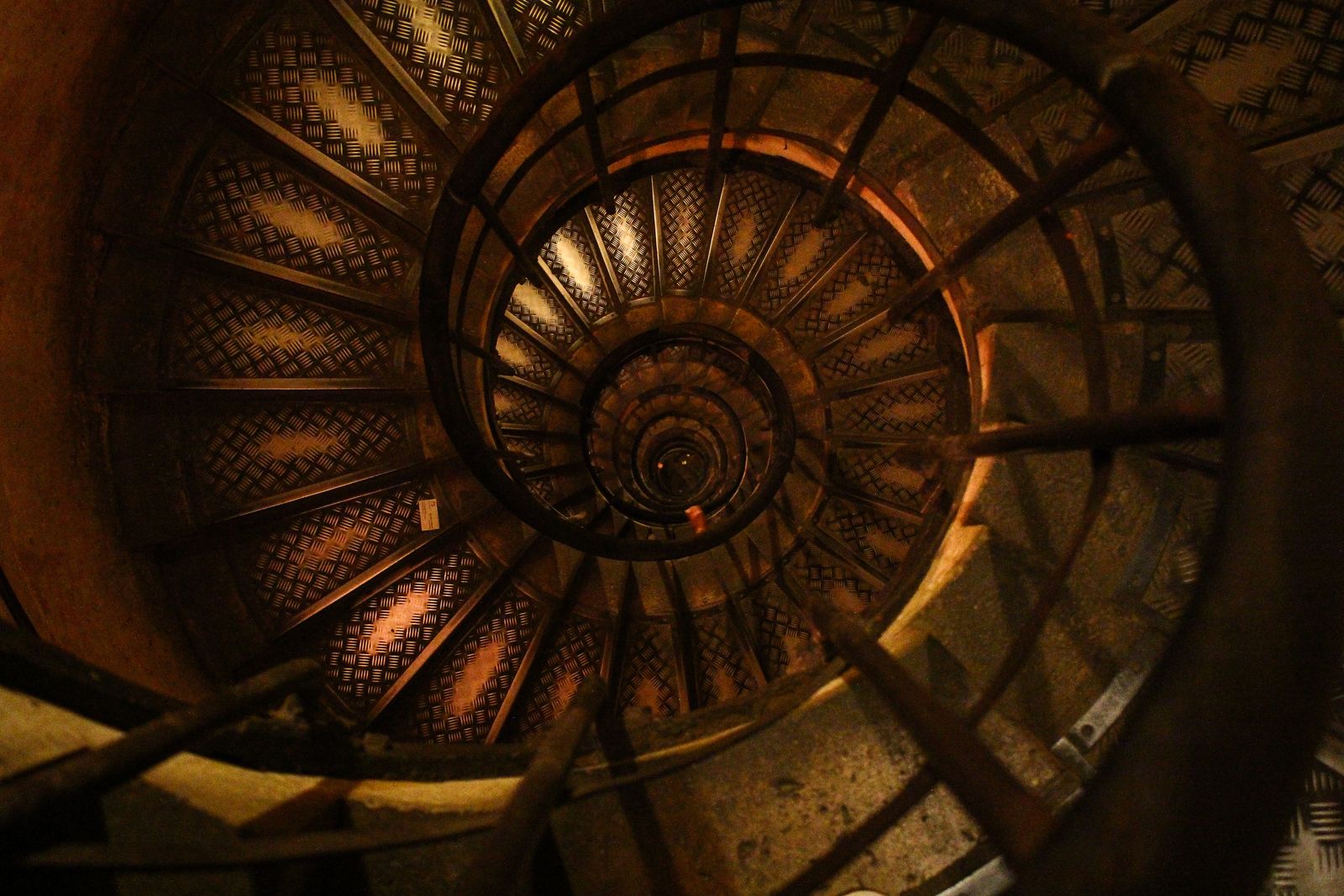 Looking down a worn spiral staircase lit in warm light