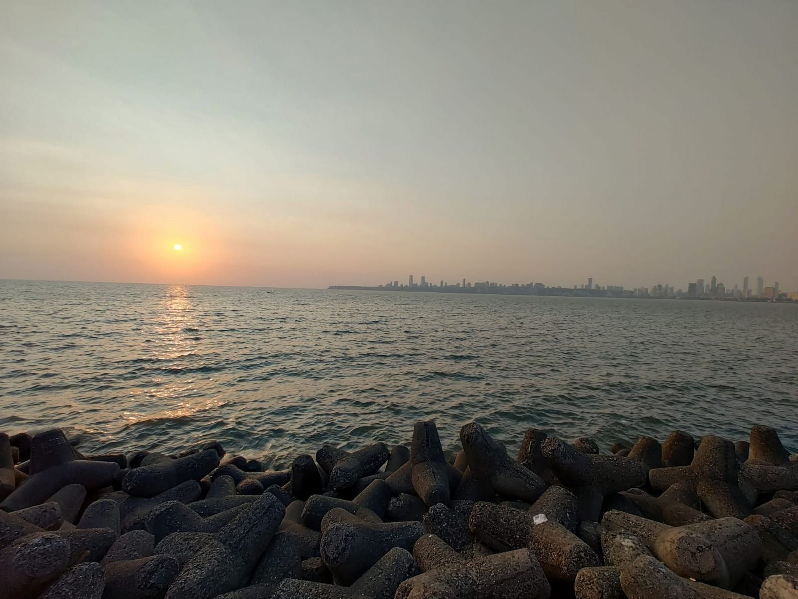 Sunset over the sea at Juhu in Mumbai, with the city skyline on the horizon
