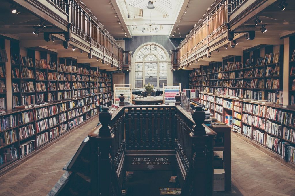 A long library hall with wooden shelves of books on two levels