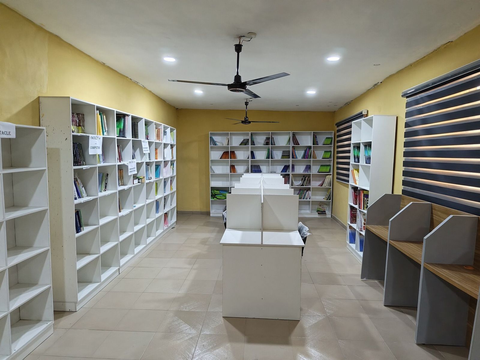An empty reading room with white shelves of files and books and study desks